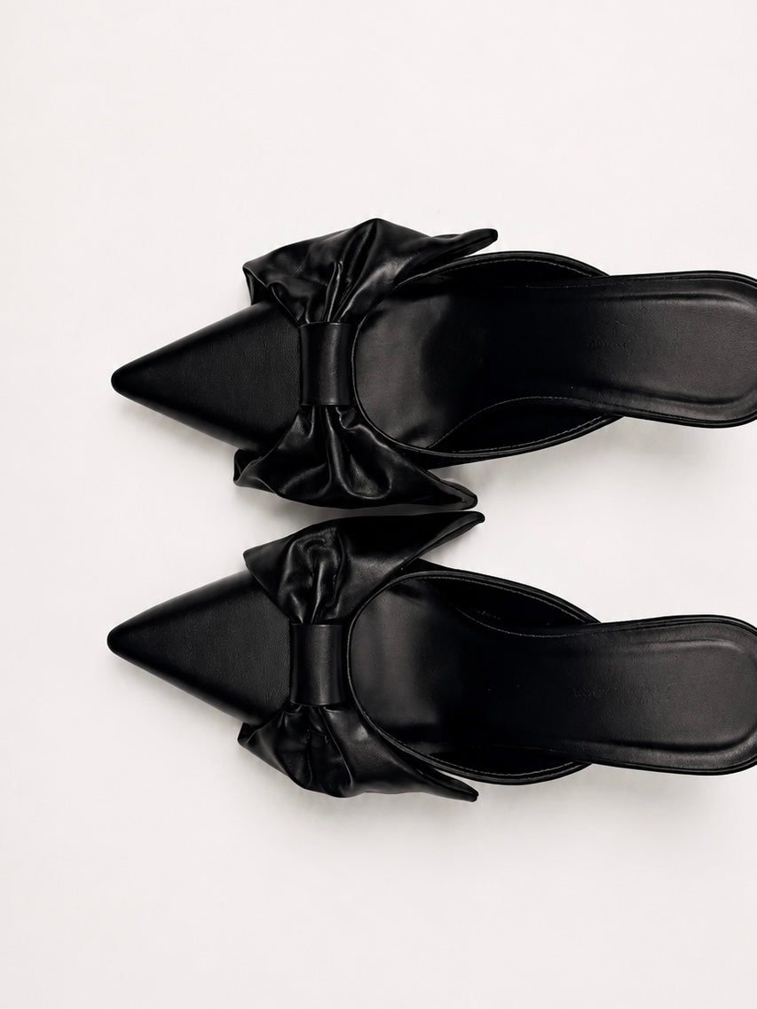 Black sandals with bow details on a white background
