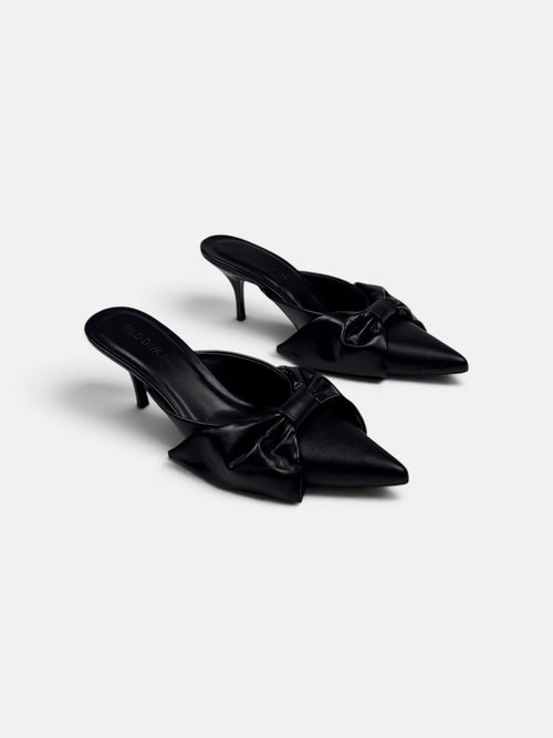 Pair of black satin mules with bow details on a white background