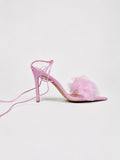 Pink high-heeled shoe with floral detail on a light gray background