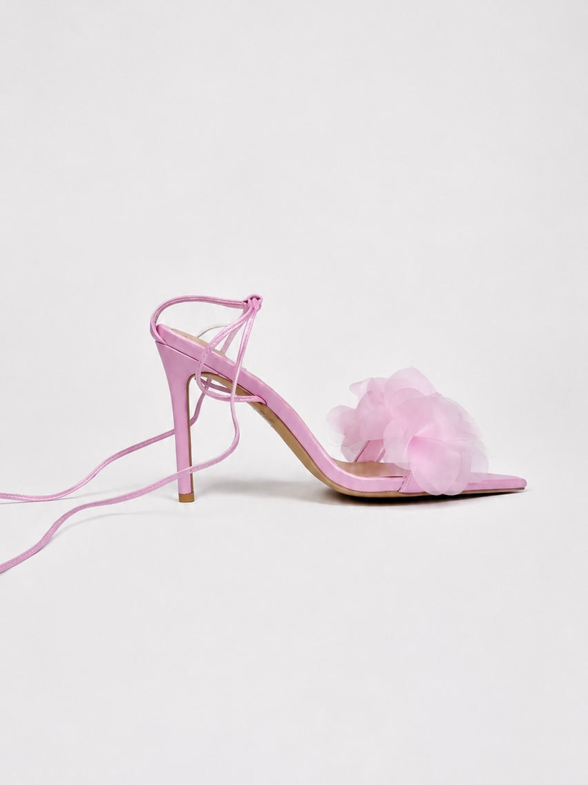 Pink high-heeled shoe with floral detail on a light gray background