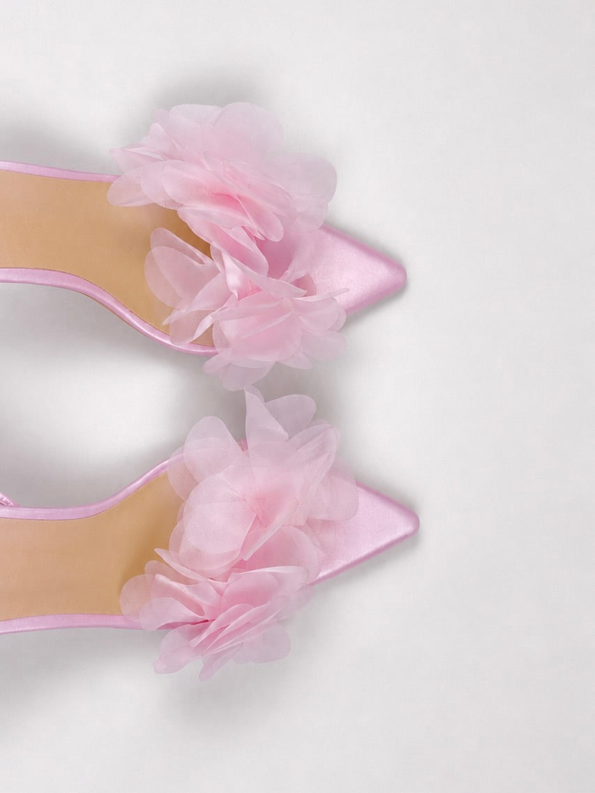 Pink high-heeled shoe with floral detail on a light gray background