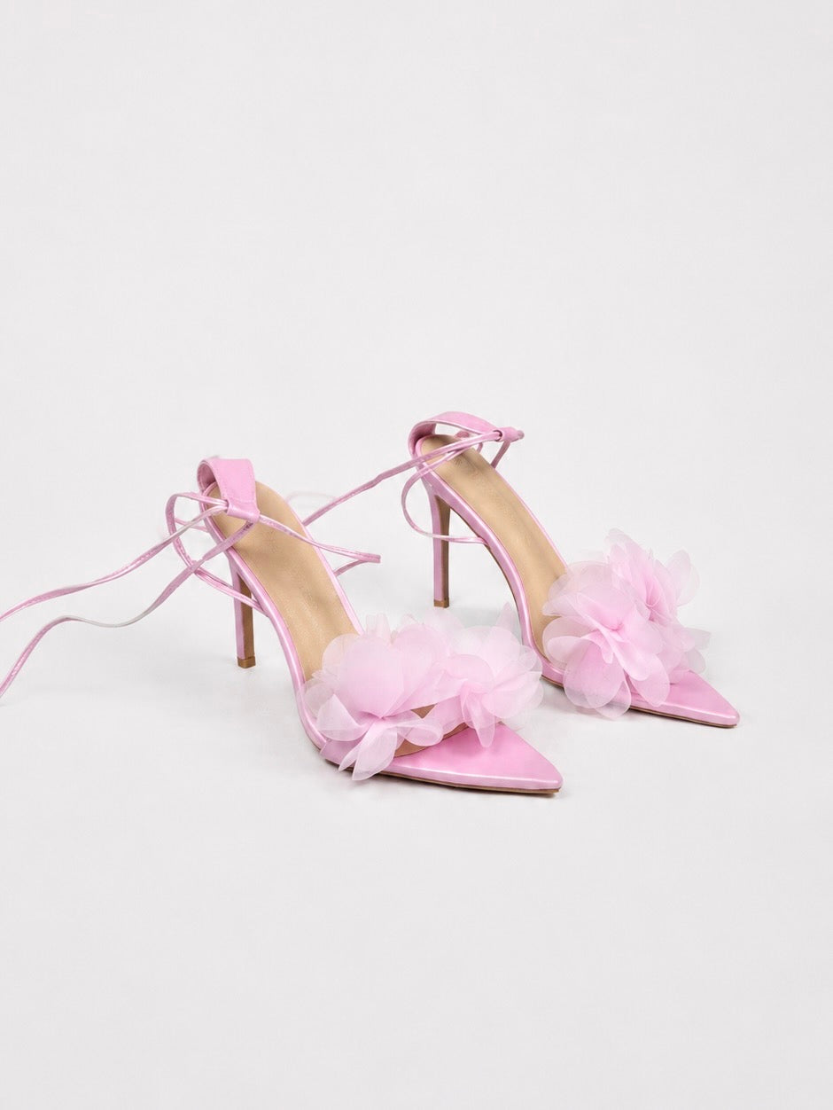 Pink high-heeled shoe with floral detail on a light gray background