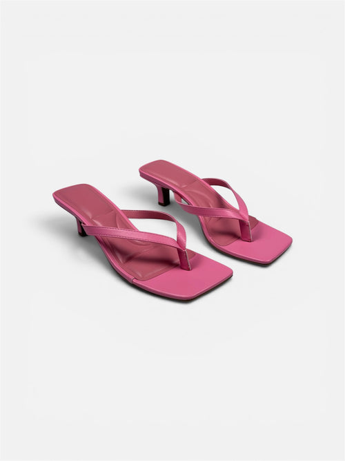 Pair of pink high-heeled sandals on a light gray background