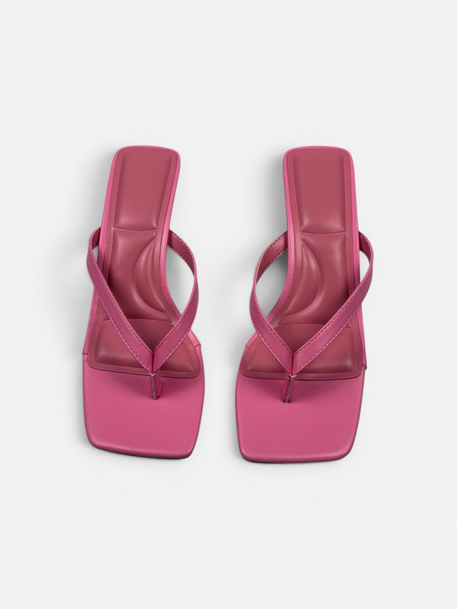 Pair of pink thong sandals viewed from above on a white background