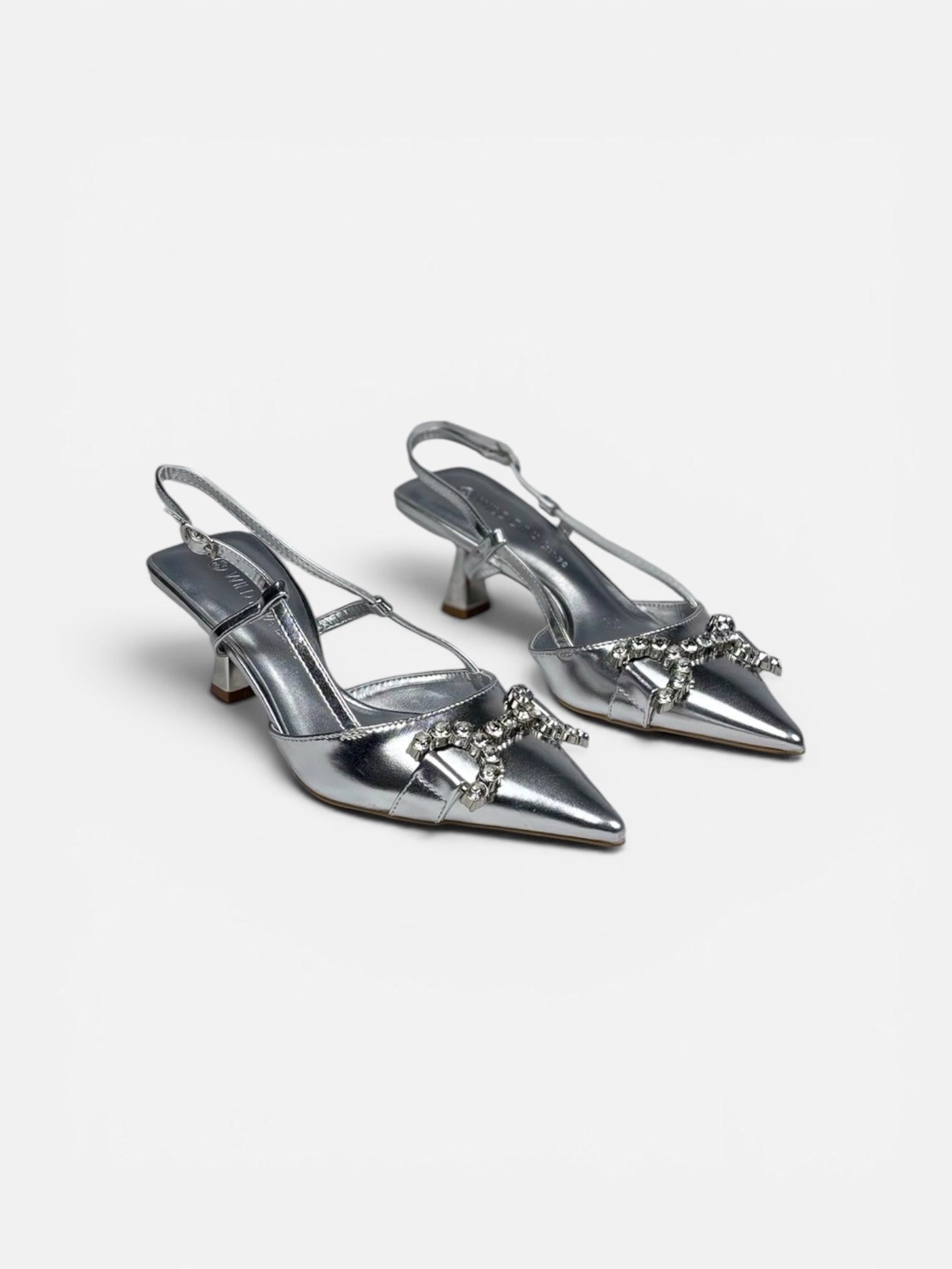 Pair of silver high-heeled shoes with embellishments on a white background