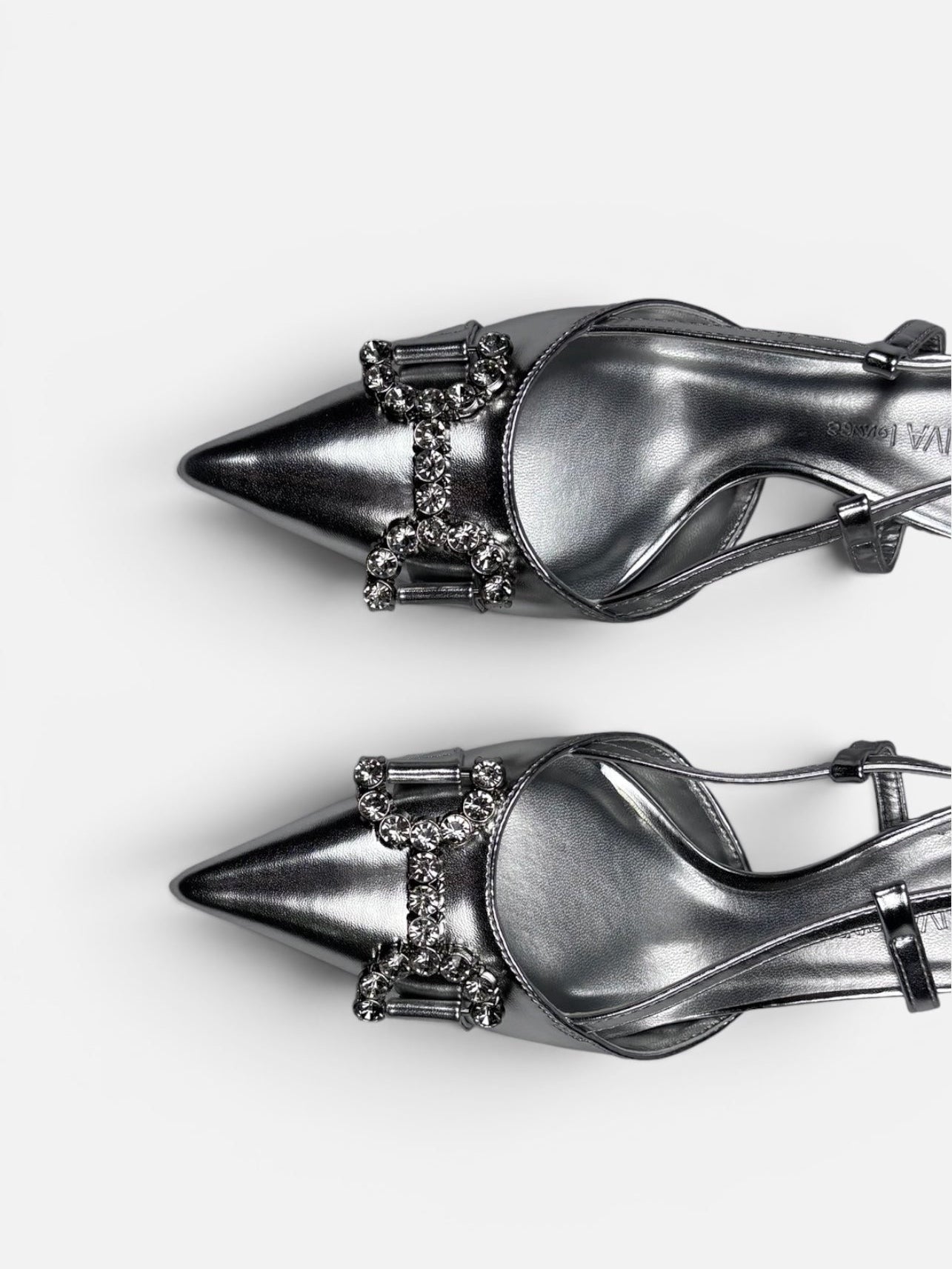 Pair of silver high-heeled shoes with embellishments on a white background