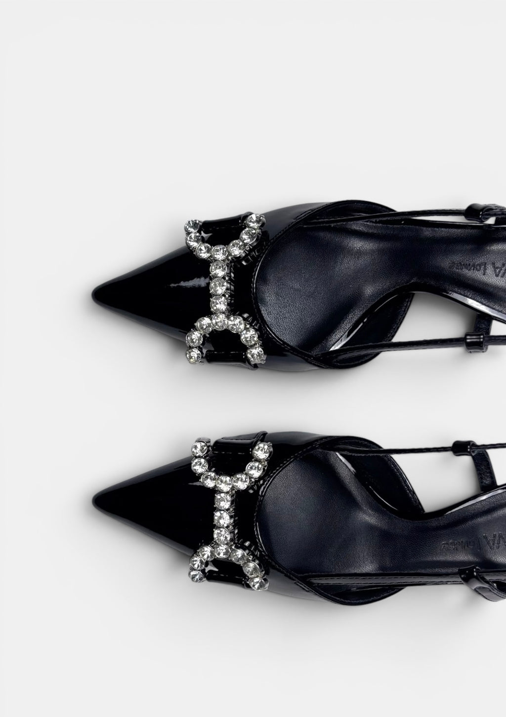Black high-heeled shoes with decorative 'H' design on a white background