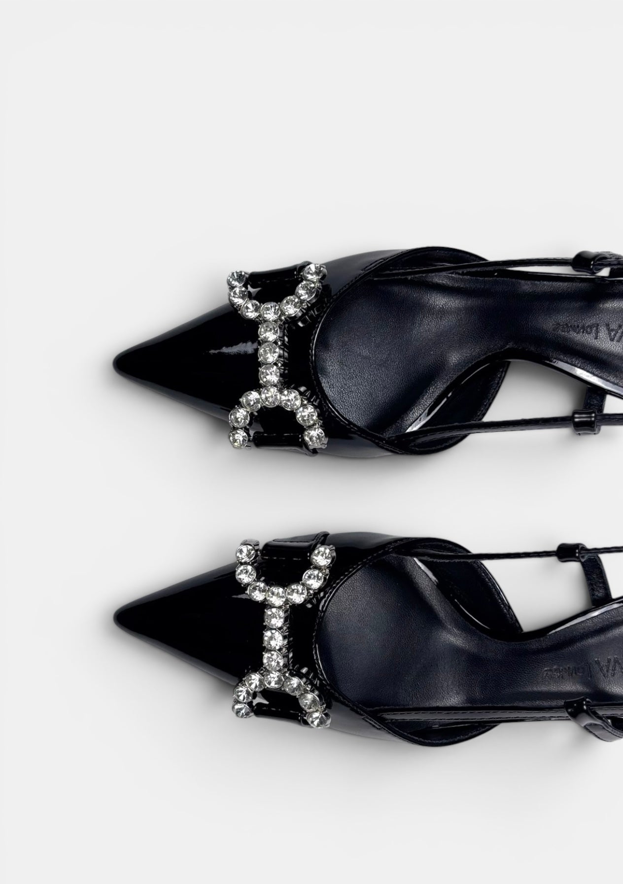 Black high-heeled shoes with decorative 'H' design on a white background