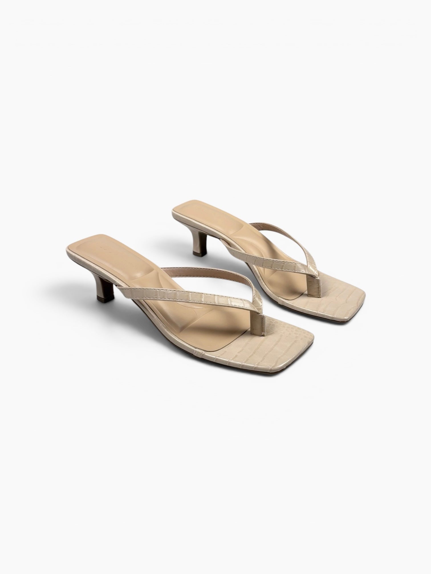 Pair of beige high-heeled sandals on a white background